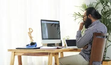 A man engaged with his laptop and computer at a desk, representing the commitment of web development professionals.