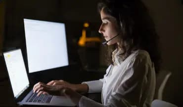 A developer woman wearing a headset and typing on a laptop, showcasing Dinoustech's dedication to transparency with expert.