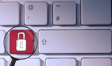 Image of a magnifying glass on a keyboard with a padlock, representing the importance of security in applications.