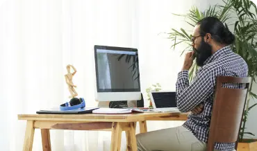 A man engaged with his laptop and computer at a desk, representing the commitment of CakePHP web development professionals.